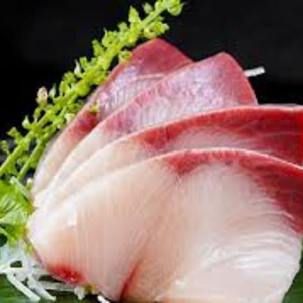 Close-up of fresh Hanabi Sushi sashimi slices, featuring red and white fish with green garnish.
